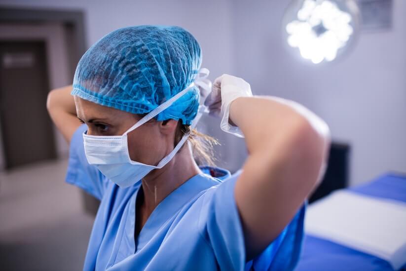 Female nurse tying her surgical mask in operation theater at a hospital